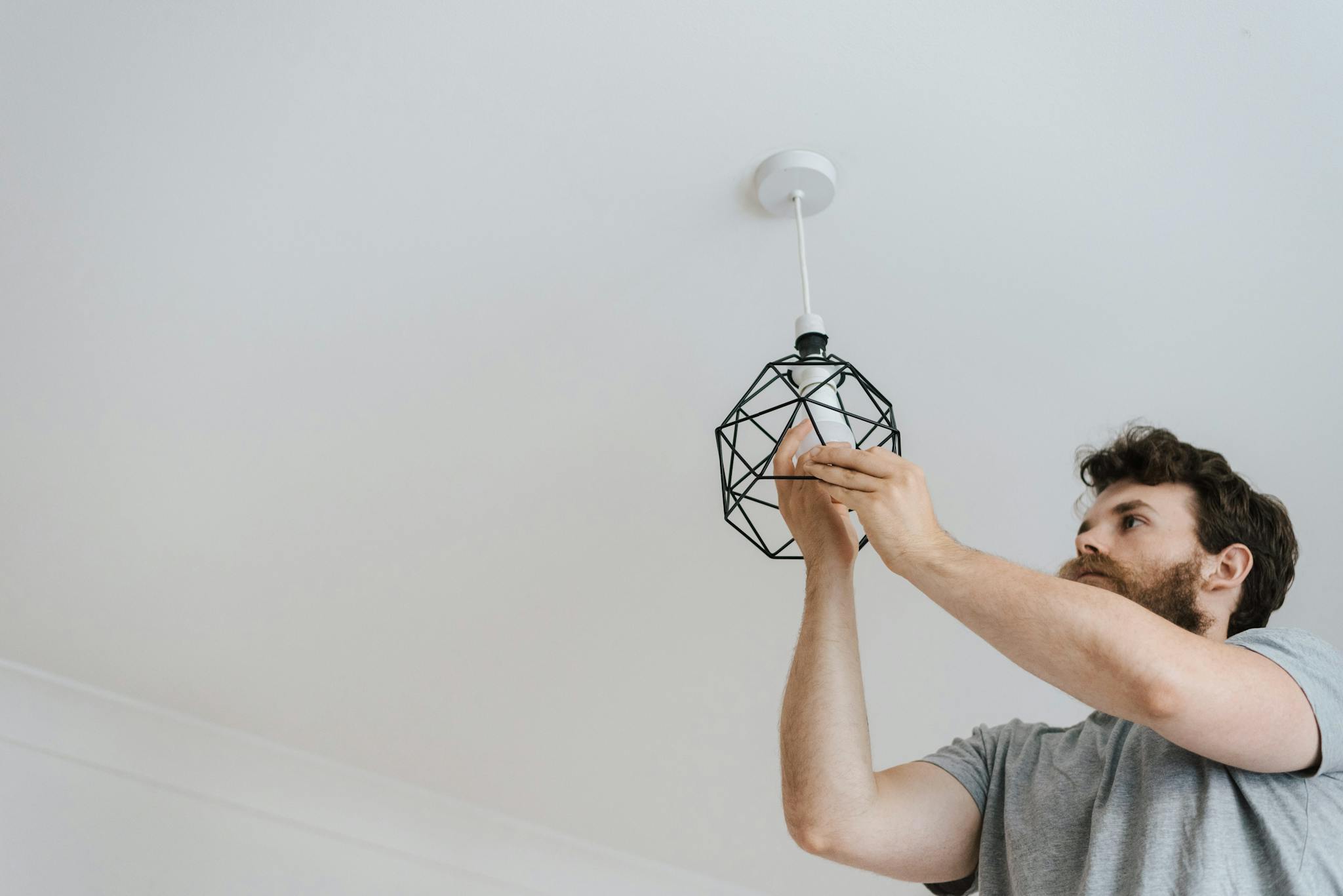 About A Professional Electrician Skillfully Installing A Modern Geometric Ceiling Lamp Indoors. 4792521 2048x1367