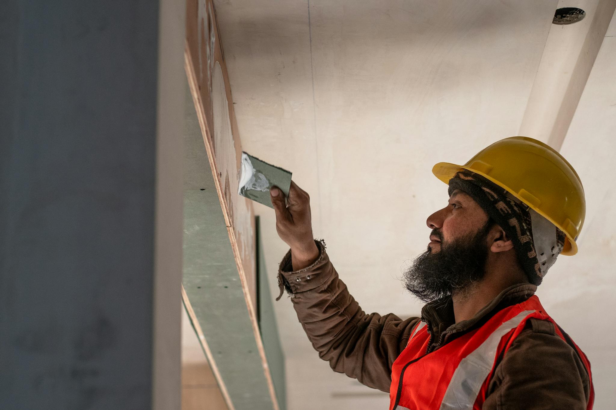 About Construction worker in Delhi applies plaster to ceiling, showcasing renovation skills.