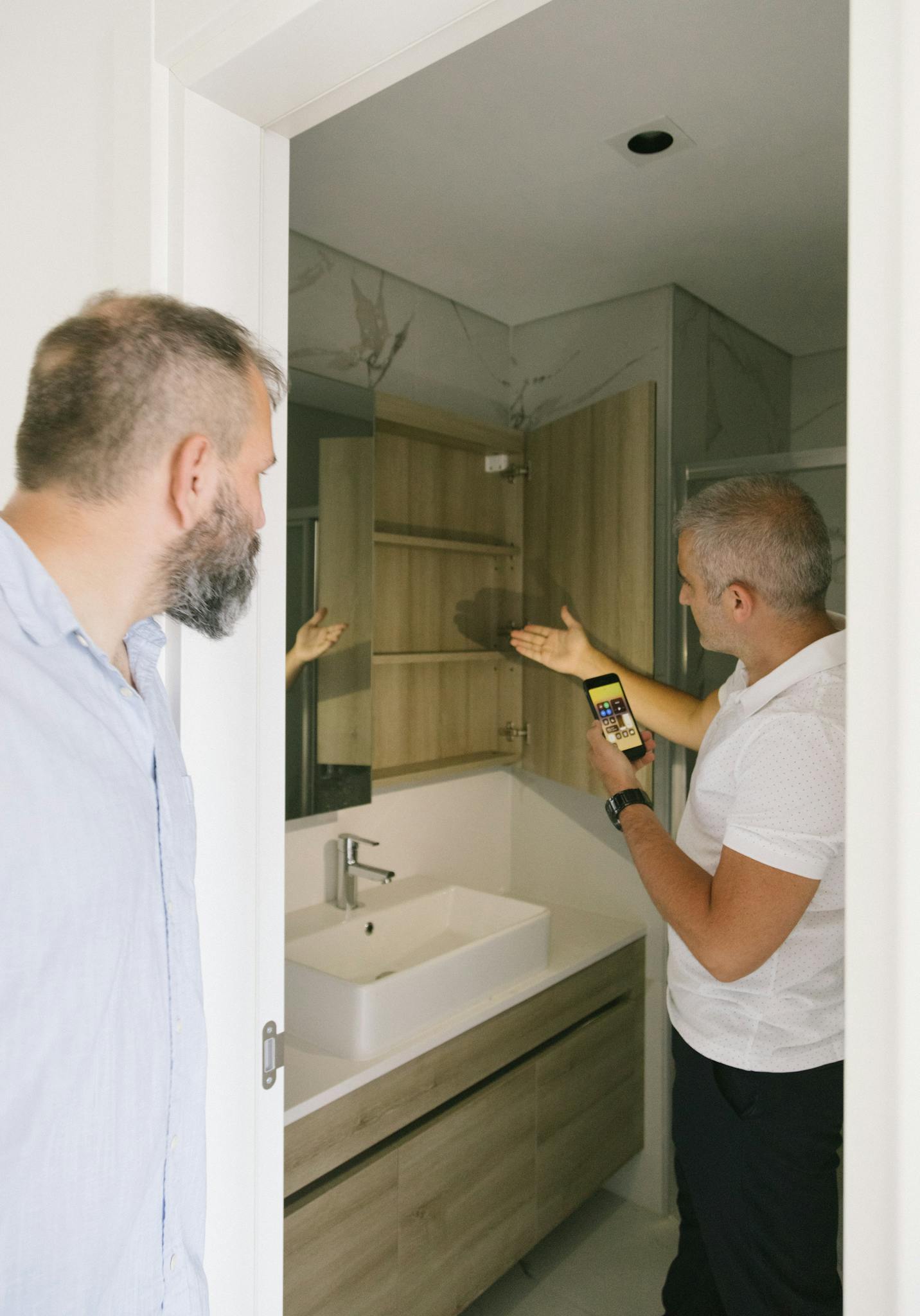 About Two Men Examining A Modern Wooden Cabinet In A Sleek Bathroom Setting Indoors. 8978568 1432x2048